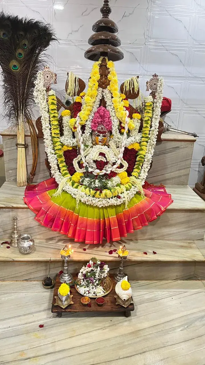 ಹಸಿರು ಎಲೆಗಳು, ಕಿರೀಟ ಮತ್ತು ಬಣ್ಣಬಣ್ಣದ ರೇಷ್ಮೆ ವಸ್ತ್ರಗಳಿಂದ ಅಲಂಕೃತಳಾದ ದೇವಿ
